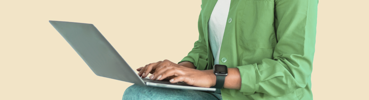 An image of a man wearing a green shirt working on a laptop.