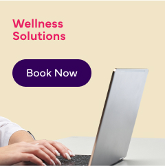 An image of a person working on a laptop with text reading: 'Wellness Solutions ' and a 'Book Now' button.